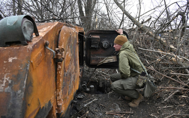 Ukraiński żołnierz przy zniszczonym rosyjskim transporterze