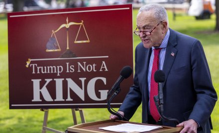 Lider senackiej mniejszości Chuck Schumer obok planszy z napisem „Trump nie jest królem”