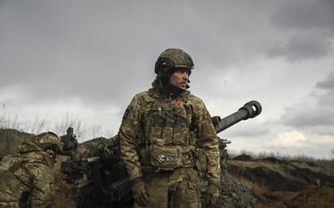 Ukraiński żołnierz stoi przed haubicą 105 mm w pobliżu Bachmutu