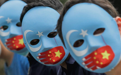Protestujący przeciwko ludobójstwu Ujgurów noszą charakterystyczne maski w barwach flagi Wschodniego