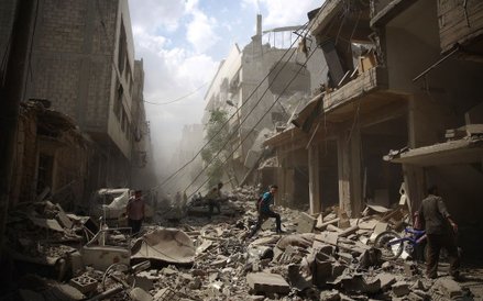 Syryjczycy na gruzach zniszczonych budynków po nalotach jakie siły wierne Baszarowi el-Asadowi przep