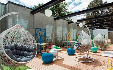 Idea Hub w Warszawie ma wewnętrzne patio,  w którym ulokowano stoliki  do pracy, kanapy, fotele, ham