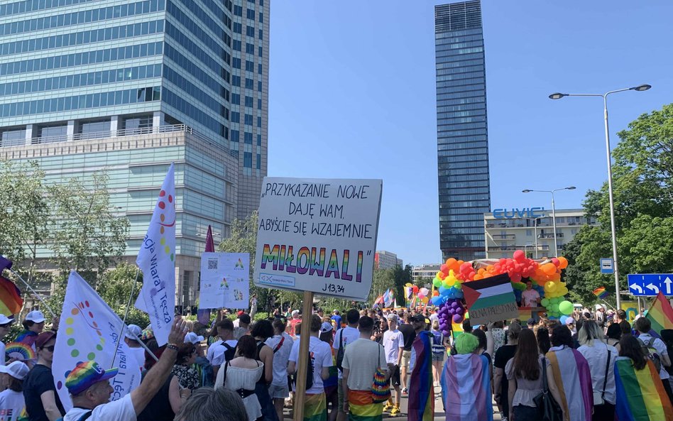 Uczestnicy Parady Równości maszerujący ulicą. Wyróżnia się transparent z cytatem biblijnym: "PRZYKAZ