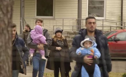 Syryjscy imigranci i łotewska wolotariuszka przed obozem dla uchodźcow na Łotwie