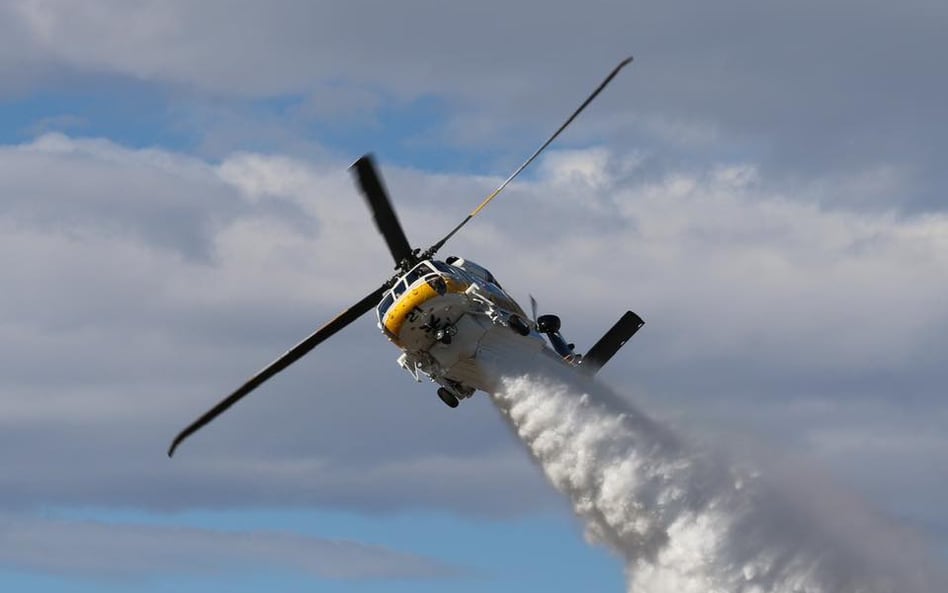 Wielozadaniowy śmigłowiec pożarniczy Sikorsky S-70i Firehawk podczas zrzutu środka gaśniczego. Fot./