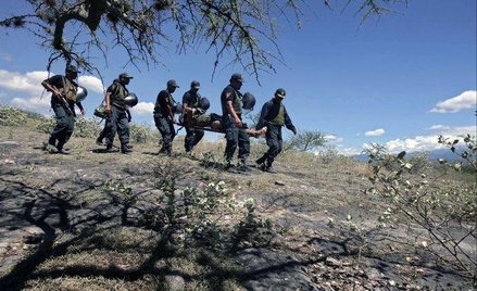 Policjanci niosą ciało zamordowanego mężczyzny