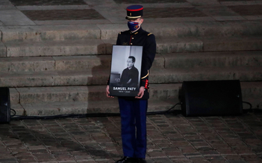 Członek Gwardii Republikańskiej trzyma portret zamordowanego Samuela Paty'ego podczas uroczystości p