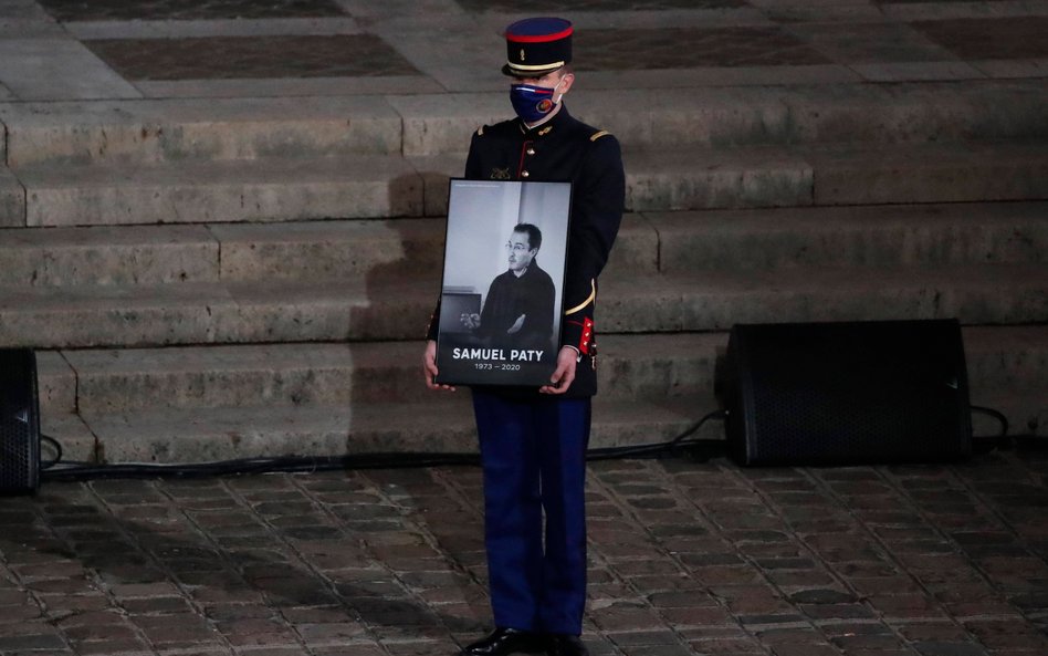 Członek Gwardii Republikańskiej trzyma portret zamordowanego Samuela Paty'ego podczas uroczystości p