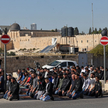 Palestyńscy muzułmanie odprawiają piątkową modlitwę na ulicy zablokowanej przez izraelskie siły bezp