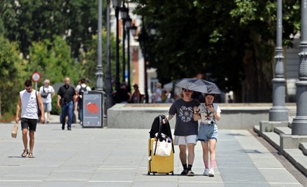 Turyści chronią się przed słońcem w pobliżu Pałacu Królewskiego w centrum Madrytu