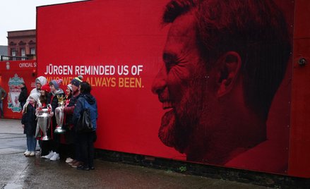 Kibice Liverpoolu pozują do zdjęć z repliką trofeum Premier League i Pucharu Ligi Mistrzów, obok wiz