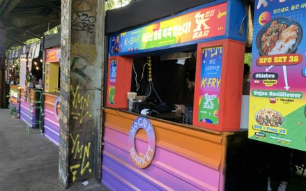 Kolorowe stoisko "K-Bar" z koreańskimi przysmakami, w tym "K-Fry" i "KFC Set",