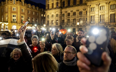 Demonstranci trzymają smartfony z włączonymi latarkami podczas wiecu zorganizowanego w odpowiedzi na
