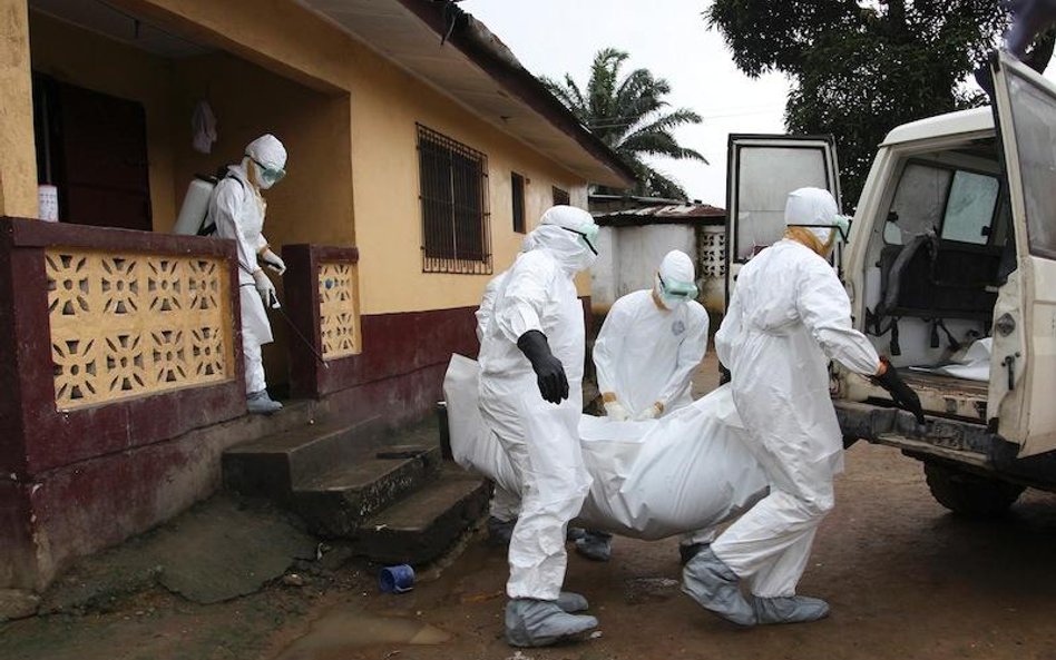 Liberia: pielęgniarze wynoszą z domu ciało ofiary wirusa Ebola.