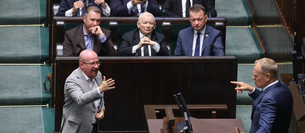 Premier Donald Tusk przemawia na sali obrad Sejmu. Przed mównicą poseł PiS Bartłomiej Wróblewski, w 
