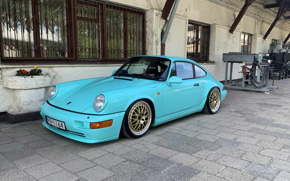 Jasnoniebieskie (aqua blue) Porsche 911 generacji 964, wyposażone w sportowe, złote felgi