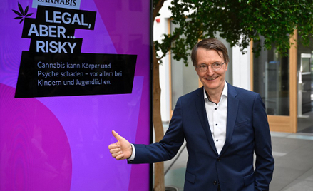 Niemiecki minister zdrowia Karl Lauterbach na tle plakatu kampanii na rzecz legalizacji marihuany