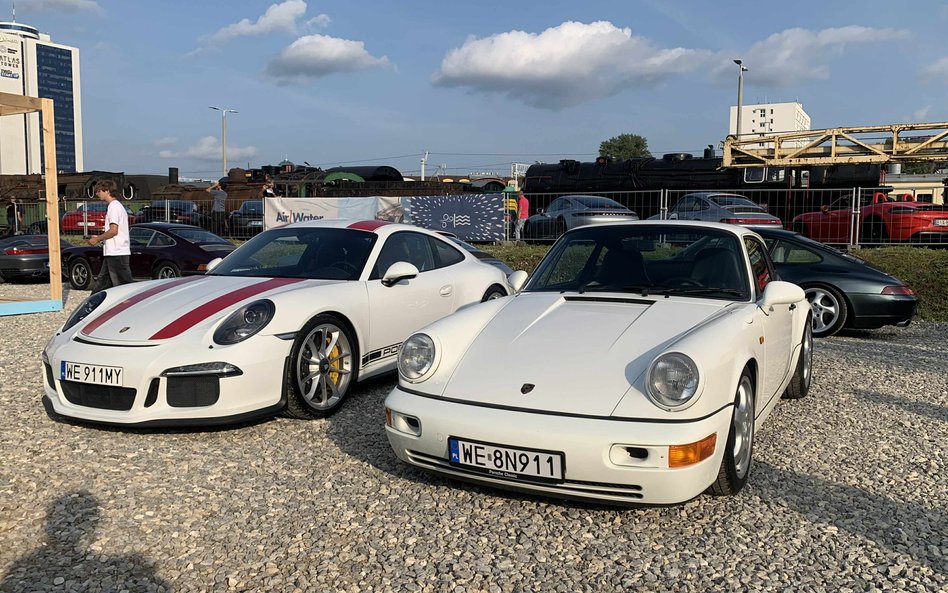 Dwa białe Porsche, w tym nowoczesny model z czerwonymi pasami wyścigowymi i klasyczny 911