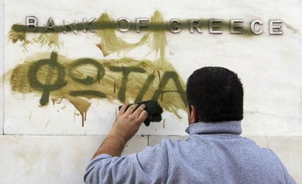 Czy Grecja wyjdzie z kryzysu? Na zdjęciu: zamazywanie słowa „pożar”, które ktoś namalował na logo Ba