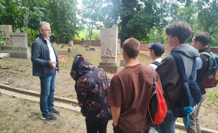 Janusz Durdziński oprowadza uczniów po nieczynnym cmentarzu ewangelickim