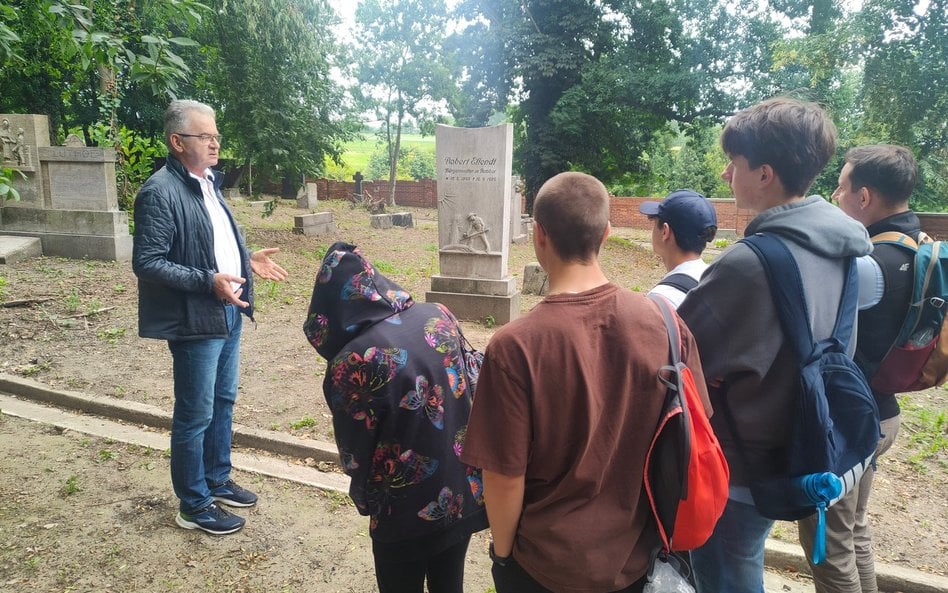 Janusz Durdziński oprowadza uczniów po nieczynnym cmentarzu ewangelickim