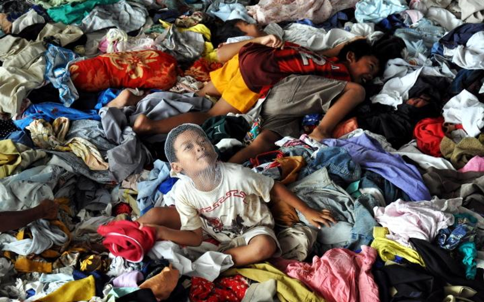 Indonezja, Sleman. Dzieci bawiące się odzieżą z darów w obozie dla uchodźców spod wulkanu Merapi