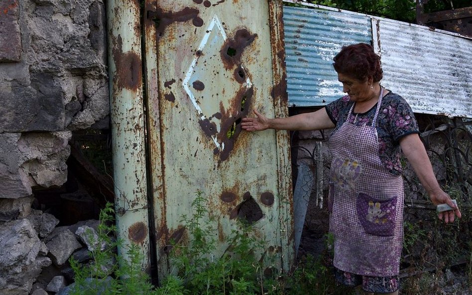 70-letnia Armenka wskazuje na bramę dziedzińca w wiosce Ajgepar w prowincji Tawusz, uszkodzoną w wyn