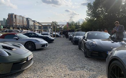 Długi rząd lśniących Porsche zaparkowanych na żwirowym placu