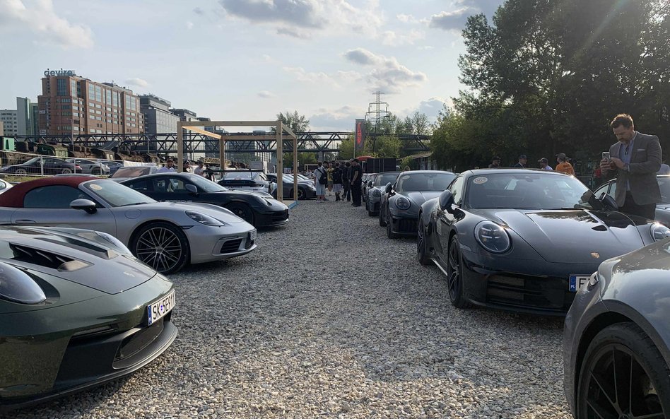 Długi rząd lśniących Porsche zaparkowanych na żwirowym placu