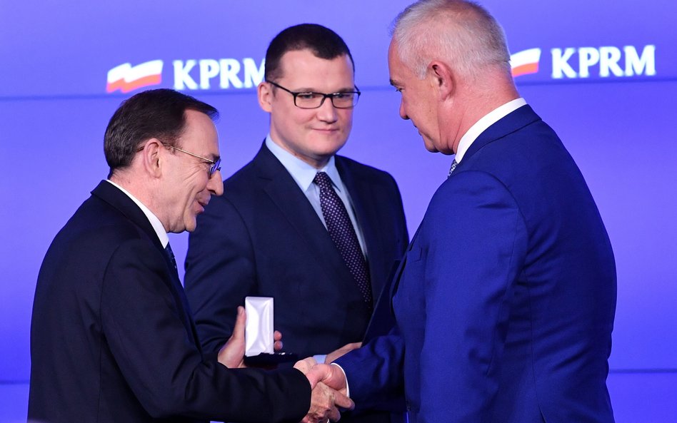 Mariusz Kamiński i Paweł Szefernaker (w środku) odznaczają Odznaką Honorową za Zasługi dla Samorządu