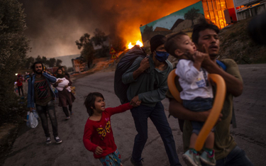 Imigranci opuszczają obóz dla uchodźców w Morii na Lesbos, który spłonął 9 września, pozostawiając b