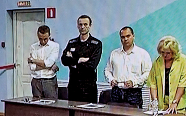 Aleksiej Nawalny (na zdjęciu w środku podczas rozprawy w sierpniu 2023 r.) od trzech lat przebywa za
