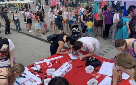 Dzieci i dorośli z zaangażowaniem rysują i kolorują zaprojektowane przez siebie wagony tramwajów