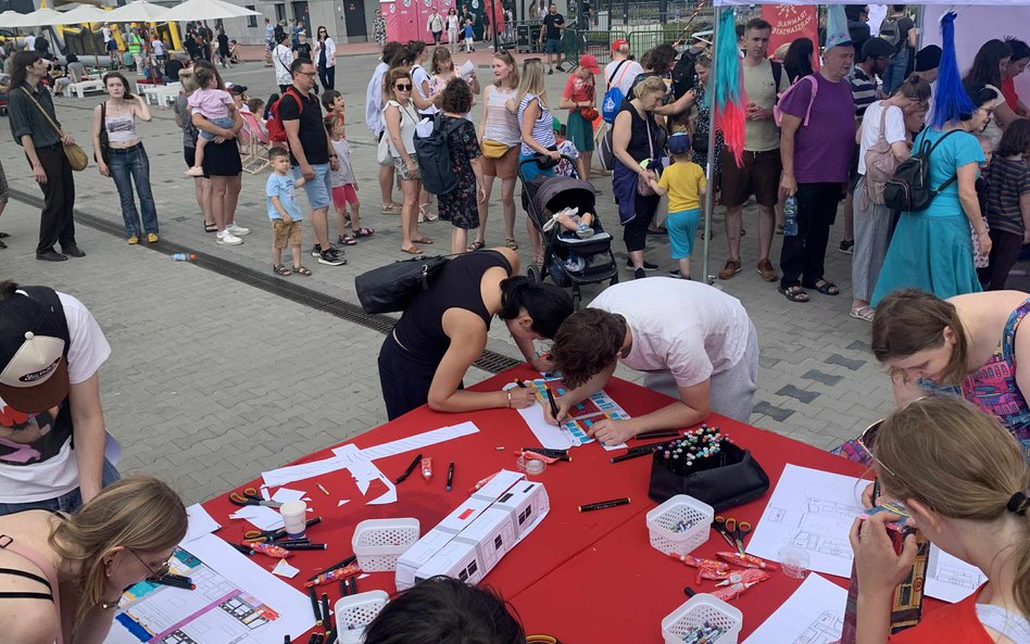 Dzieci i dorośli z zaangażowaniem rysują i kolorują zaprojektowane przez siebie wagony tramwajów
