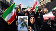 Proreżimowa demonstrantka w Iranie trzyma w ręku grafikę przedstawiającą na pierwszym planie Modżtab