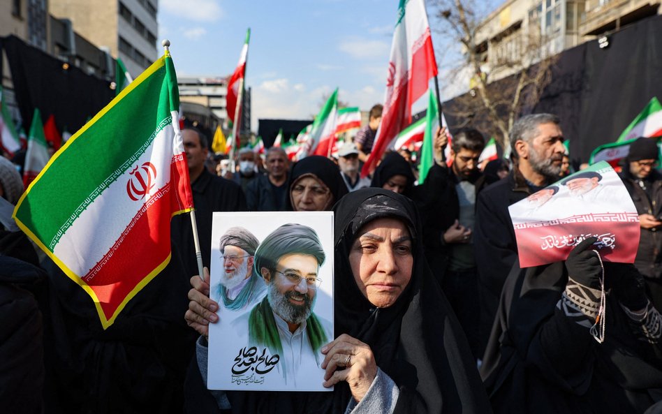 Proreżimowa demonstrantka w Iranie trzyma w ręku grafikę przedstawiającą na pierwszym planie Modżtab