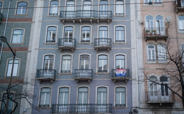 Tabliczka „Na sprzedaż” wisi na balkonie mieszkania przy alei Almirante Reis w Lizbonie