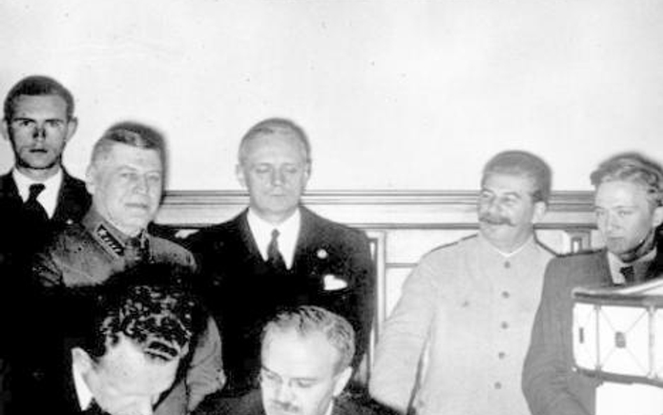 Wiaczesław Mołotow (podpisuje układ), za nim - Joachim von Ribbentrop, obok - Józef Stalin, 23 sierp