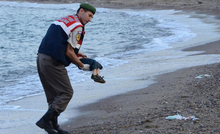 Turecki policjant podnosi ciało trzyletniego Aylana Kurdi na wybrzeżu Bodrum