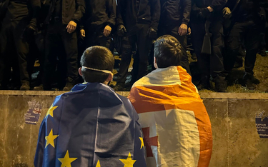 Sandro, owinięty flagą UE, przed szpalerem policjantów na fotografii, która stała się symbolem gruzi