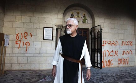Zakonnik przed klasztorem Latrun. Po lewej hebrajski napis „Jezus to małpa”
