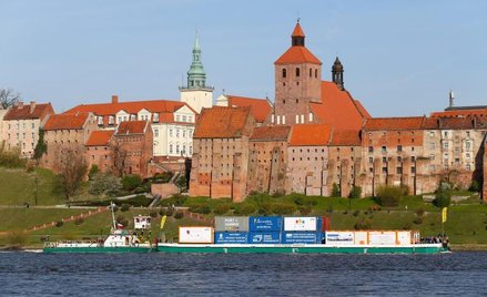 Pchacz z barką pełną kontenerów mija Grudziądz.