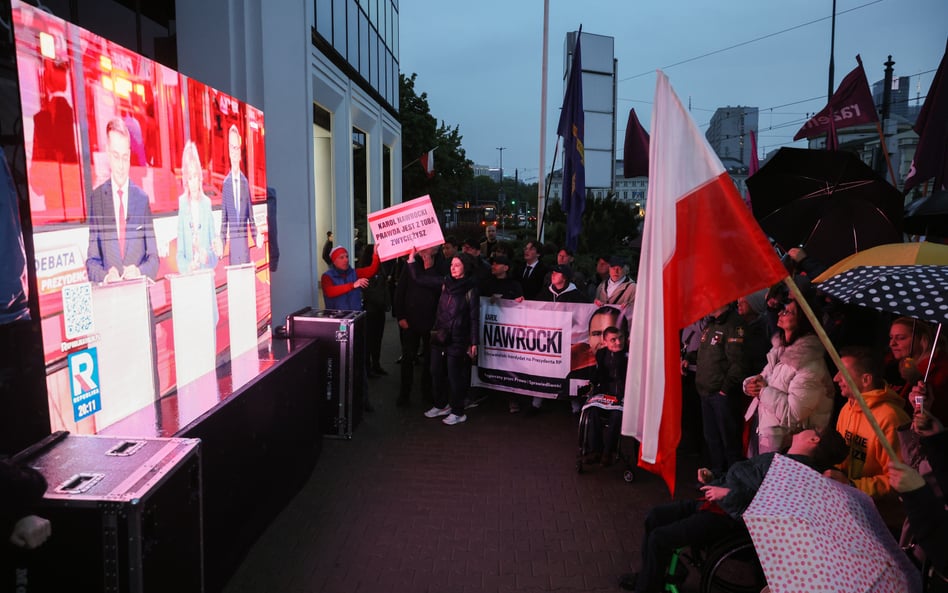 Zwolennicy kandydatów oglądają debatę na telebimie przed siedzibą TV Republika