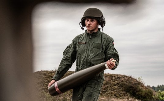 Polski żołnierz niosący pocisk kal. 155 mm.