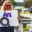 Kobieta trzyma znak „We Are Q” w kolejce do wzięcia udziału w wiecu „Make America Great Again” w Wil