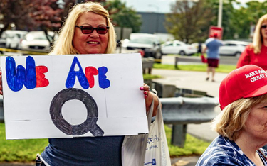 Kobieta trzyma znak „We Are Q” w kolejce do wzięcia udziału w wiecu „Make America Great Again” w Wil