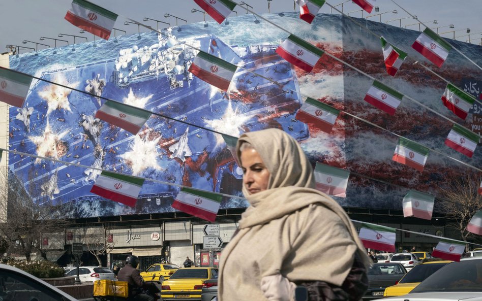 Irańska kobieta przechodzi obok budynku państwowego w centrum Teheranu w Iranie pokrytego gigantyczn