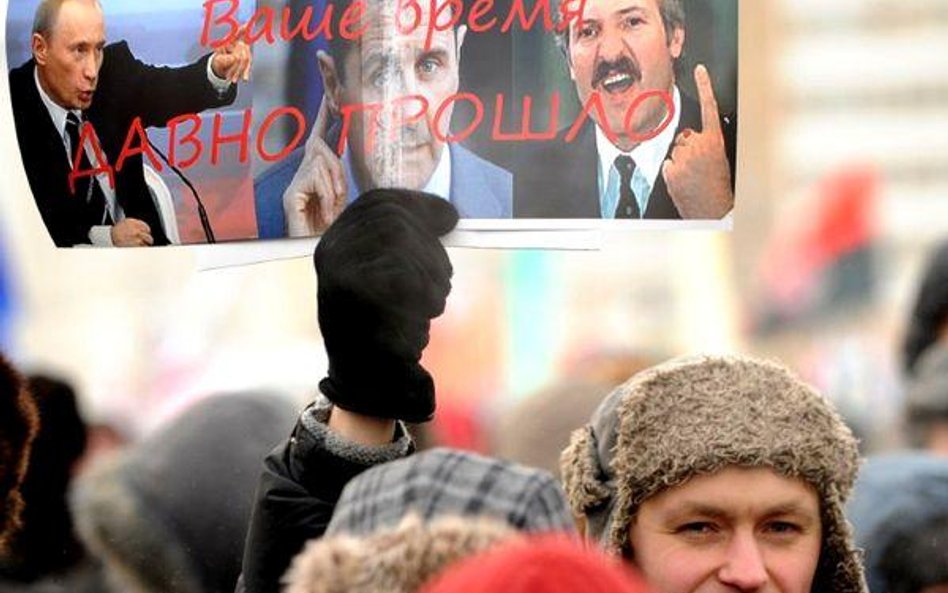 Mężczyzna trzyma plakat ze zdjęciem Aleksandra Łukaszenki