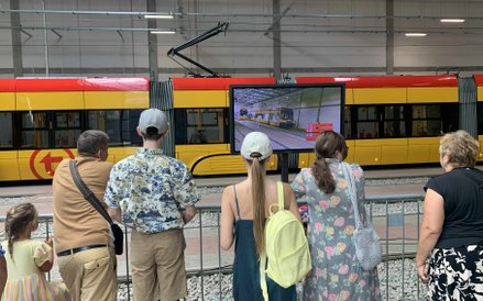 Widownia z zainteresowaniem śledzi zmagania motorniczych, wyświetlane na dużym ekranie