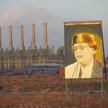 Pozłacany portret libijskiego przywódcy Muammara Kaddafiego (1942–2011) na tle rafinerii ropy naftow